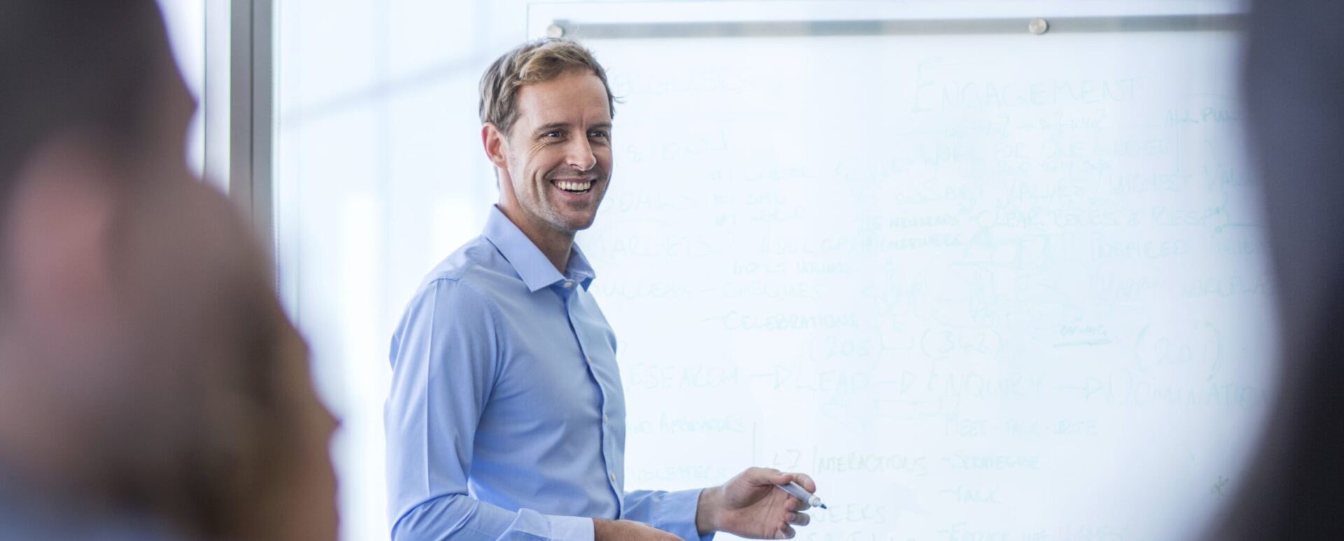 Man drawing on a whiteboard during a meeting.